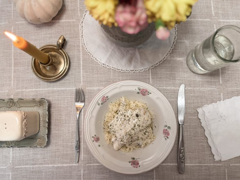 A set table, floral plate of food, vase of flowers, candle