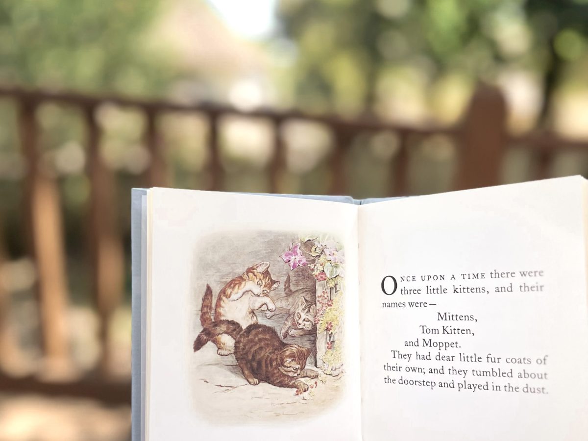 open page of Tales of Tom Kitten by Beatrix Potter, backyard in background