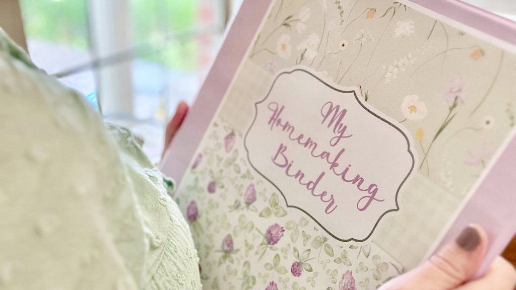 Woman holding pink and green feminine floral homemaking binder